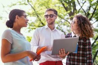 Cheerful male student holding his laptop