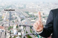 Businessman hand pointing location search bar over blur city scr