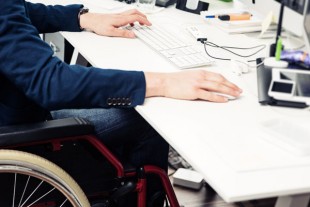 Man Sitting In Wheelchair Working In Modern Office