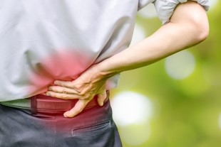 close up of a  man holding his back in pain, isolated on white b