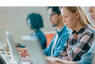 Row of Multi Ethnic Students Working on the Laptops while Listen