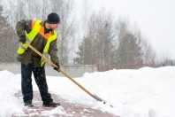 Man worker in uniform shoveling snow