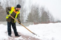 Man worker in uniform shoveling snow