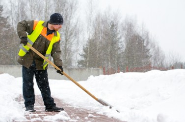 Man worker in uniform shoveling snow