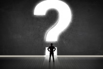 Business man looking at wall with a bright question mark