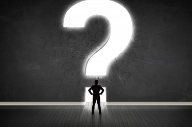 Business man looking at wall with a bright question mark