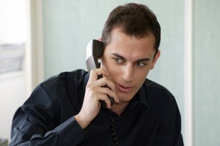 Jeune homme au bureau au téléphone