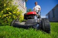 A man mowing the front lawn with focus on the front wheel