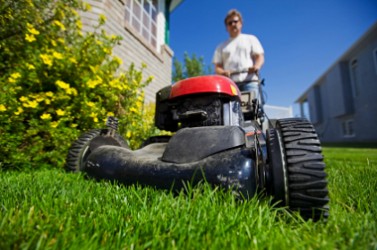 A man mowing the front lawn with focus on the front wheel
