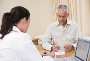 Doctor with laptop and man in doctor's office