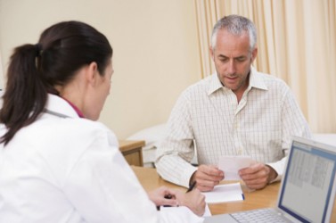 Doctor with laptop and man in doctor's office